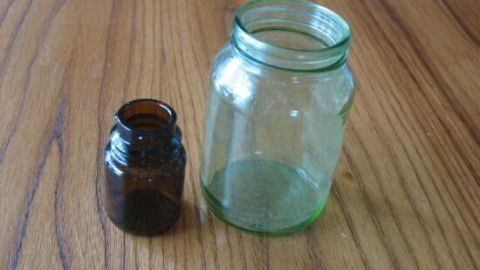 Zwei kleine Vasen stehen auf einem Holztisch, eine grüne große und eine braune kleine, bereit, individuell gestaltet zu werden.