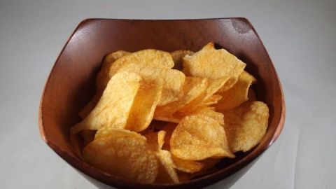 Knusprige Chips liegen in einer Holzschale und warten darauf, wieder genießbar gemacht zu werden.