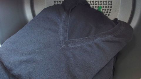 Schwarze Wäsche liegt sauber im Trockner und wartet darauf, sofort gefaltet zu werden, um Platz zu schaffen.
