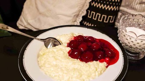 Milchreis schmeckt am besten wenn man Ihn kurz vor dem Verzehr durch ein saftiges Steak ersetzt! Milchreis mit fruchtiger Kirschsoße liegt auf einem Teller, daneben steht eine Zuckergefäße. Gemütliche Atmosphäre.