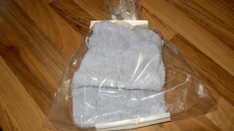 Ein kalter Umschlag aus blauer, weicher Tuchware liegt verpackt auf einem Holzboden, bereit zur Anwendung gegen Schmerzen.