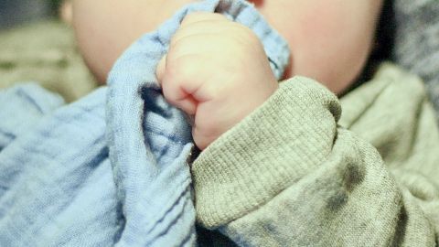 Ein Baby greift mit seiner kleinen Hand eine kalte Mullwindel, um die Symptome des Zahnens zu lindern.