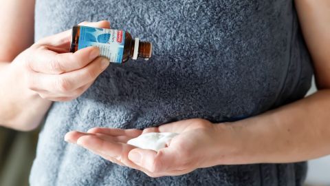 Eine Person trägt japanisches Heilpflanzenöl in die Hand, um es mit einer Bodylotion zu vermischen.