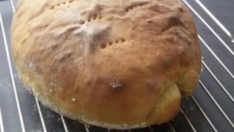 Ein goldenbraunes Siegerländer Kartoffelbrot liegt frisch gebacken auf einem Kuchengitter in einer modernen Küche.