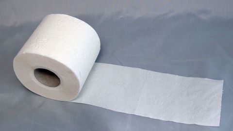 Eine Rolle Toilettenpapier liegt auf einem grauen Untergrund, während ein Blatt abgerollt wird, um Durchfall zu behandeln.