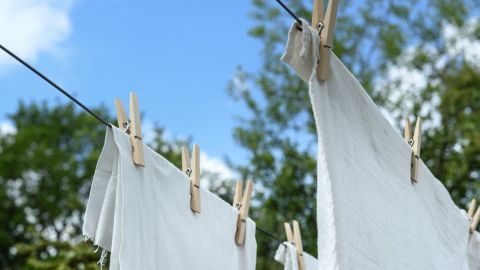 Weißes Wäsche hängt frisch gewaschen an einer Leine im Freien, um unter blauem Himmel zu trocknen.
