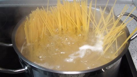 Ein Topf mit kochendem Wasser, in dem Spaghetti zubereitet werden, sprudelt und zeigt die langen, weichen Nudeln.