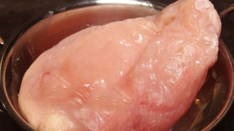 Beim Geflügelkauf sparen - ein ganzes Huhn kaufen, zerlegen und einfrieren. Eine frische Hühnerbrust liegt in einer Schüssel auf einem Tisch, bereit zum Kochen und Sparen beim Geflügelkauf.