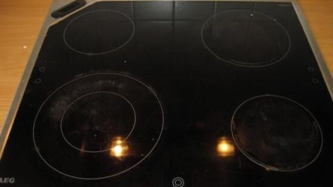 Ein glaskeramisches Kochfeld zeigt eingebranntes Material, während Sonnenlicht auf die Oberfläche fällt.