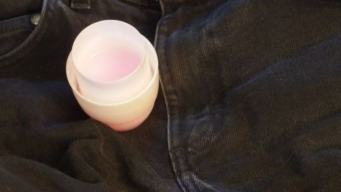 Bei dunkler Wäsche immer Flüssigwaschmittel verwenden, die Wäsche bleicht dann nicht so schnell aus. Ein Flüssigwaschmittel steckt in einer dunklen Jeans, bereitet sich auf die Wäsche von dunkler Wäsche vor.