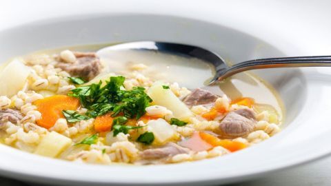 Ein voller Teller Kohlrabieintopf mit Bauchfleisch ist appetitlich angerichtet, mit frischen Kräutern garniert.