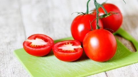 Vesper- oder Schneidebretter aus (weißem) Kunststoff mit Tomaten- oder Kräuterrückständen oder auch "älteren" Spuren werden so wieder schön hell. Auf einem grünen Kunststoffschneidebrett liegen frische Tomaten, einige halbiert, in einer hellen Küchenszene.