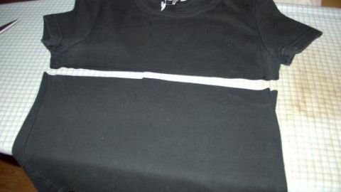 Ein schwarzes Shirt liegt auf einem Tisch, während es in der Mitte mit einem weißen Band zum kreativen Verlängern markiert ist.