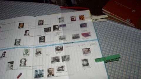 Ein Schulbuch liegt geöffnet auf einem Tisch und zeigt Bilder von historischen Persönlichkeiten, ergänzt durch handschriftliche Notizen.