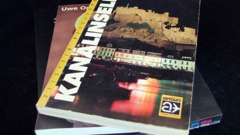 Zwei Bücher liegen übereinander, eines zeigt eine abgebildete Stadtansicht bei Nacht, mit dem Titel „KANALINSELN“.