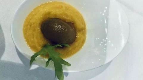 Ein cremiges Süßkartoffelpüree in einer Schüssel, garniert mit einem Schokoladeneis und frischen Kräutern.