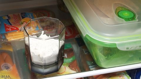 Ein Glas mit Mehl steht im Kühlschrank, um Gerüche zu absorbieren, umgeben von Lebensmitteln und Aufbewahrungsboxen.