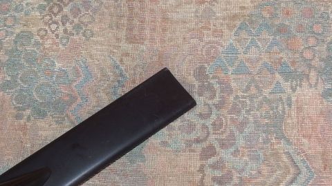 Ein schwarzes Staubsaugerrohr liegt auf einem gemusterten Teppich, was auf eine mögliche Verstopfung hindeutet.