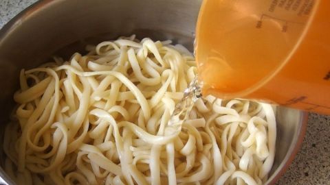 Nudeln werden mit Wasser in einen Topf gegossen, um verklebte Spaghetti wieder locker zu bekommen.