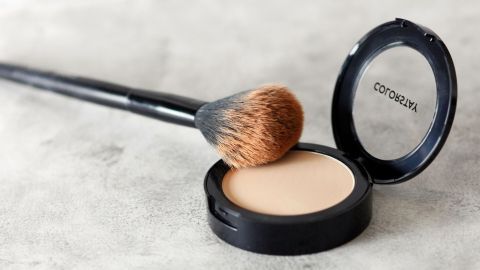 Wenn es schnell gehen muss und man keine Zeit zum Haare waschen hat, dann kann man seinen leicht fettigen Haaransatz mit Puder kaschieren. Ein Puder mit Pinsel liegt offen auf einer glatten Oberfläche, ideal für die Pflege bei leicht fettigem Haaransatz.
