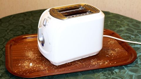Krümelfreie Arbeitsplatte, Tisch oder Schrank mithilfe eines Tabletts: Viel Spaß beim Ausprobieren. Ein Toaster steht auf einem Tablett und toastet, um eine krümelfreie Arbeitsfläche zu gewährleisten.