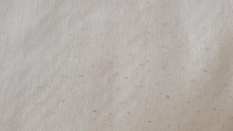 Ein weicher Stoff zeigt einige kleine Wollknötchen (Pilling), die im Licht sichtbar sind und die Textur stören.