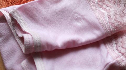 Feinwäsche waschen in einem Kopfkissenbezug: Durch diese Wäschehülle wird die Feinwäsche geschützt und sieht länger wie neu aus. Ein rosa Kopfkissenbezug liegt zusammengefaltet auf einer orangefarbenen Decke und wird zum Schutz der Feinwäsche genutzt.