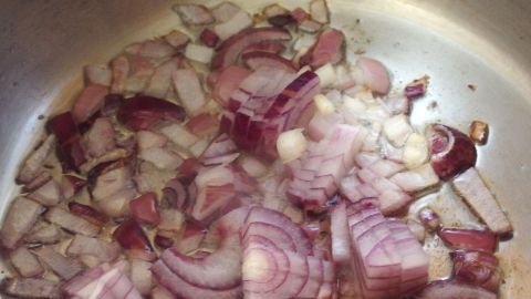 Kochgeruch wird vertrieben, indem man ein mit Essig getränktes Tuch zwischen Topf und Deckel legt. Zwiebeln braten in einer Pfanne, was Gerüche beim Kochen erzeugt. Ein feuchter Dampf umgibt das geschnittene Gemüse.