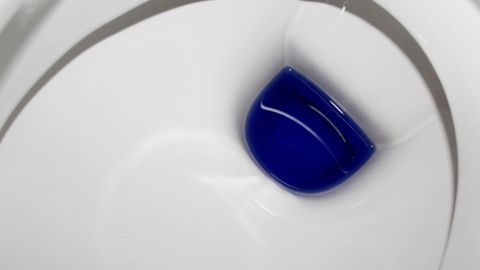 Ein blauer Reinigungstropfen schwimmt in einer sauberen Toilettenschüssel und sorgt für Frische gegen Kalk.