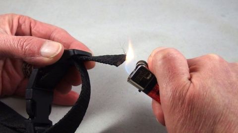 Hände halten einen Feuerzeug, während sie Kordelenden versiegeln. Der Hintergrund ist neutral und unifarben.