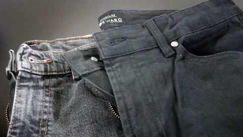 Ausgeblichene Jeans liegen neben intensiver gefärbten Jeans auf einem dunklen Untergrund, bereit zum Nachfärben.