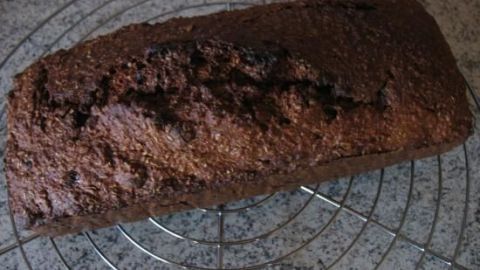 Ein frisch gebackenes Kleiebrot liegt auf einem Kuchengitter, bereit zum Genießen mit Honig und Aprikosen.