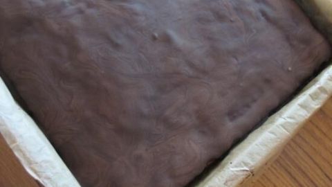 Ein saftiger Nusskuchen mit Zucchini liegt in einer Backform auf einem Holztisch und wartet auf den Genuss.
