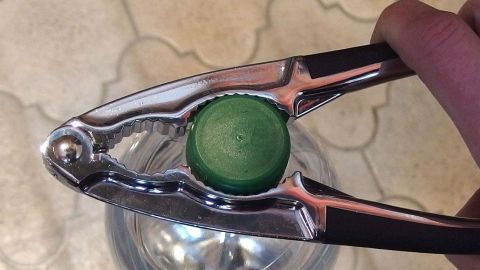 Eine Flasche mit Drehverschluss wird mit einem speziellen Öffner in einer Küche geöffnet, um den Inhalt zugänglich zu machen.