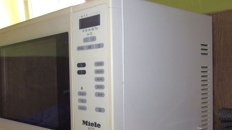 Ein Mikrowelle steht auf einer Arbeitsfläche und wird gereinigt, um Glaskeramik-Herd und Mikrowelle außen zu pflegen.