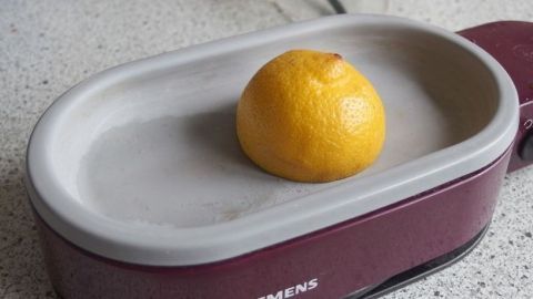 Eine Zitrone liegt auf einer Kochplatte, während sie erhitzt wird, um den Wasserkocher zu entkalken.