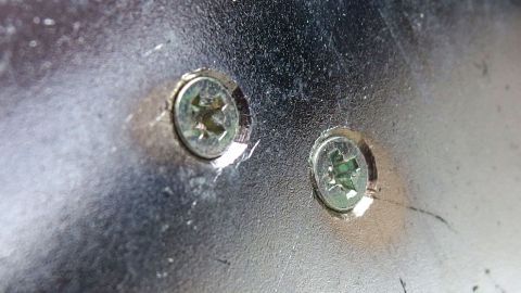 Zwei zerstörte Schrauben sitzen in einer Metalloberfläche, bereit zur Entfernung mit geeignetem Werkzeug.