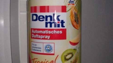 Ein automatischer Duftspraybehälter steht in einem Diffusor und versprüht tropische Düfte in einem Badezimmer.