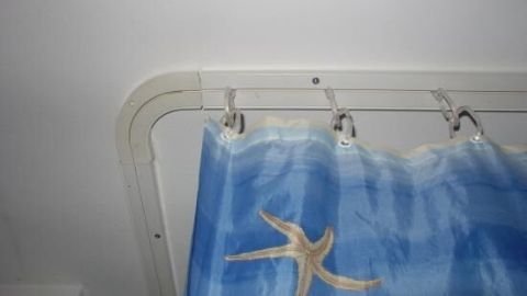 Eine Duschvorhangstange hält einen blauen Duschvorhang mit einem Muster auf, der in einem Badezimmer angebracht ist.