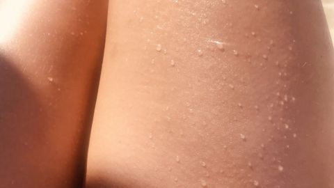 Glänzende Beine mit Wasserperlen zeigen, dass nach der Dusche Juckreiz oder Hautirritationen auftreten können.