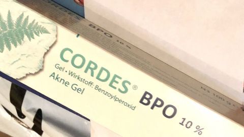 Eine Tube mit dem Cordes Akne Gel, das Benzoylperoxid enthält, liegt auf einer Oberfläche zur Hautpflege.