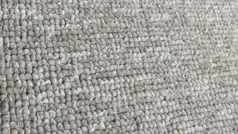 Um Rotweinflecken aus Teppichen zu entfernen, kann Essig helfen. Einfach den Fleck mit Essig und Wasser behandeln und sanft einarbeiten. Der Artikel erklärt, wie du den Teppich retten kannst. Beiger Teppich in Nahaufnahme zeigt seine strukturierte Oberfläche.