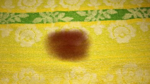 Jodflecken mit Natriumthiosulfat-Lösung (Na2S2O3) entfernen. Gibt es günstig in der Apotheke. Ein gelbes Tuch mit einem Jod-Fleck in der Mitte liegt vor einem grünen Streifen und weißen Blumen.