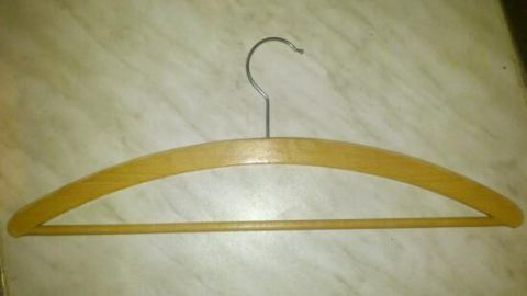 Ein Holzkleiderbügel liegt auf einer hellen, glatten Oberfläche und könnte als Laternenstab für St. Martin verwendet werden.