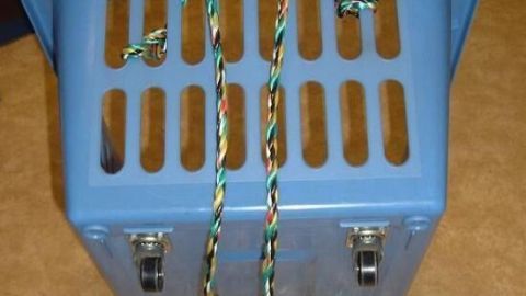 Ein blauer Wäschekorb mit Rädern steht auf einer hellen, gefliesten Fläche, bereit, Wäsche zu transportieren.