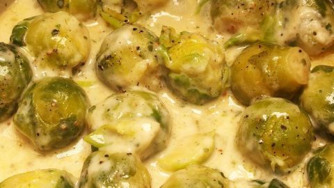 Wenn man die Rosenkohl-Röschen vor dem Kochen halbiert und die gelben Blätter entfernt, bekommt das Ganze keinen bitteren Geschmack. Rosenkohl wird in einer cremigen Sauce zubereitet, um den bitteren Geschmack zu reduzieren. Er liegt in einer Pfanne.