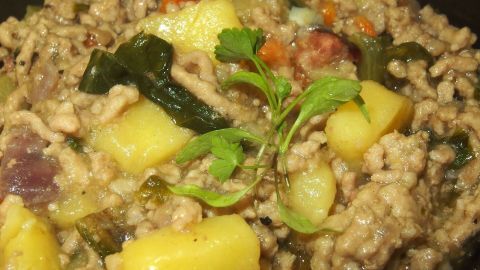 Ein Eintopf mit Kartoffeln und Hackfleisch, gemischt mit Chinakohl und frischen Kräutern in einer Schüssel.