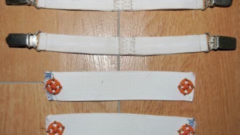 Straps mit Metallclips liegen auf einem Holzfußboden, bereit, um Hosenbeine stramm in Stiefel zu stecken.