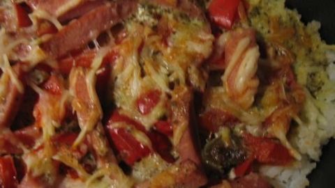 Ein Reis-Paprika-Tomaten-Auflauf wird warm serviert, gemischt mit roten Paprika und Käse über einer Reisbasis.