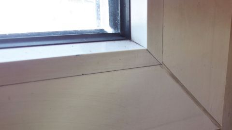 Weiße Fensterrahmen zeigen Rückstände. Backofenspray wird aufgetragen, um die Reinigung im Innenraum zu erleichtern.